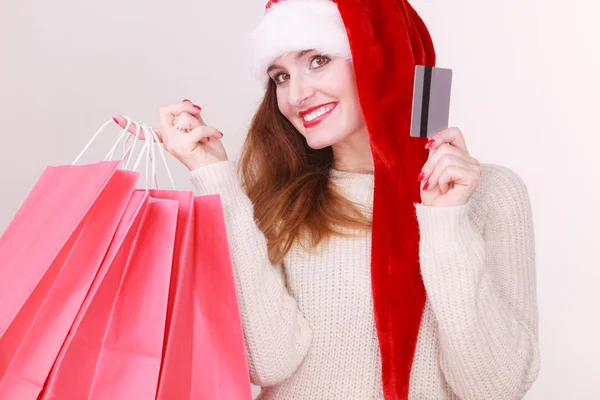 Vrouw in KERSTMUTS houdt credit card en boodschappentassen. — Stockfoto