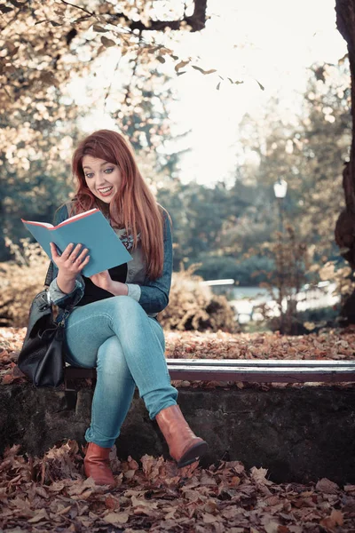 Joven mujer está leyendo libro en el parque . — Foto de Stock