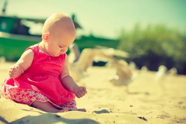 Pequeno bebê sentado e brincando na praia — Fotografia de Stock