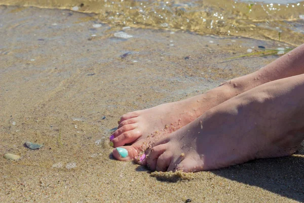 Pies de mujer con esmalte de uñas sobre arena — Foto de Stock