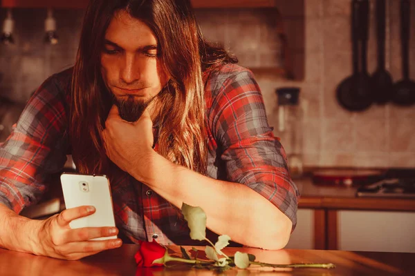 Ανήσυχος άνθρωπος με τριαντάφυλλο και κινητό τηλέφωνο. — Φωτογραφία Αρχείου