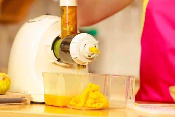 Making orange juice in juicer machine in kitchen — Stock Photo, Image