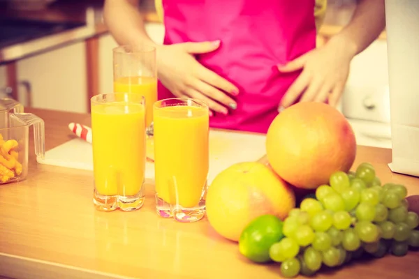 Kvinna med färsk frukt och juice i kök — Stockfoto