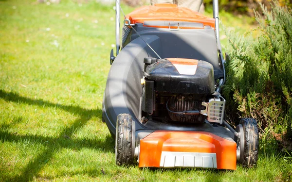 Gardening. Mowing green lawn with red lawnmower — Stock Photo, Image