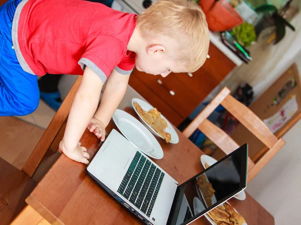 Niño pequeño con portátil en la mesa en casa . — Foto de Stock