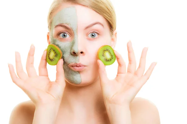 Cuidado com a pele. Mulher em máscara de barro com kiwi no rosto — Fotografia de Stock