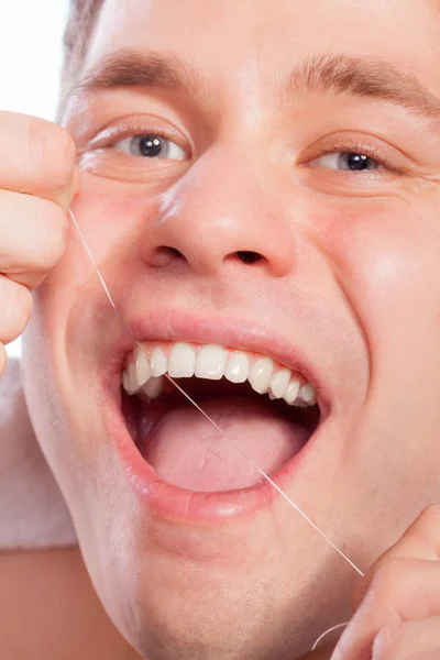 Young man cleaning her white teeth with dental floss — Stock Photo, Image