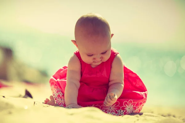 Pequeno bebê sentado e brincando na praia — Fotografia de Stock
