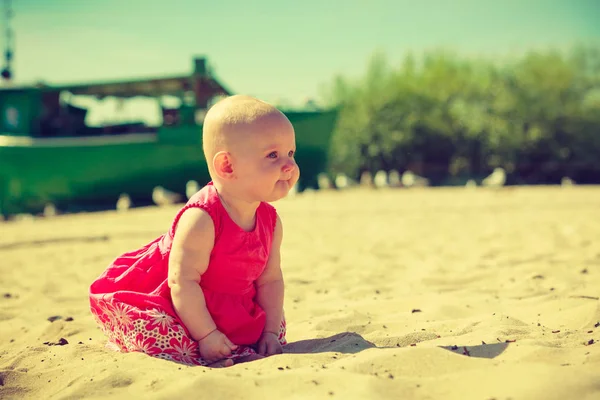 Pequeno bebê sentado e brincando na praia — Fotografia de Stock