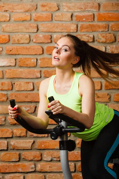 Mulher ativa usando bicicleta de exercício no ginásio . — Fotografia de Stock