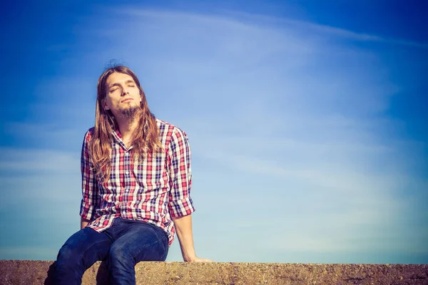 Mann lange Haare entspannend im Freien Himmel Hintergrund — Stockfoto