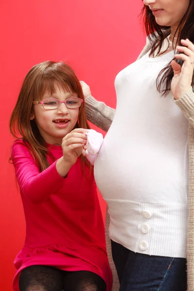 Pregnant woman with toddler girl holding baby shoes — Stock Photo, Image