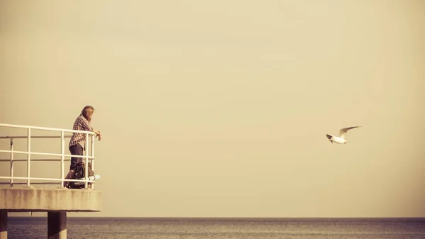 男子徒步旅行者背包上码头，海上景观 — 图库照片