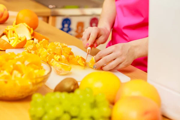 Mujer ama de casa en cocina corte de frutas naranja — Foto de Stock