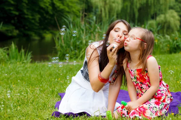 母と公園でシャボン玉を吹く少女. — ストック写真