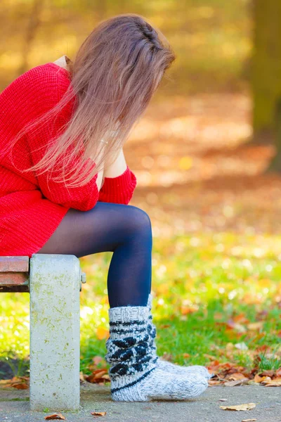 Sorglig kvinna sitter på bänk i parken — Stockfoto