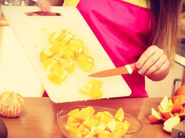 Femme au foyer dans la cuisine coupe des fruits orange — Photo