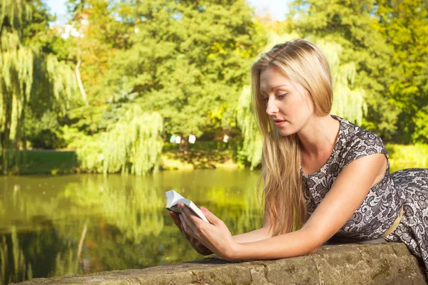Žena sedí v parku, relaxační a pomocí telefonu — Stock fotografie