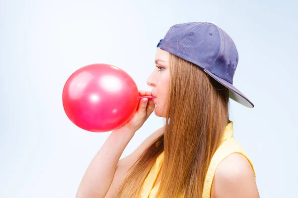 Mujer adolescente inflando globo rojo . — Foto de Stock