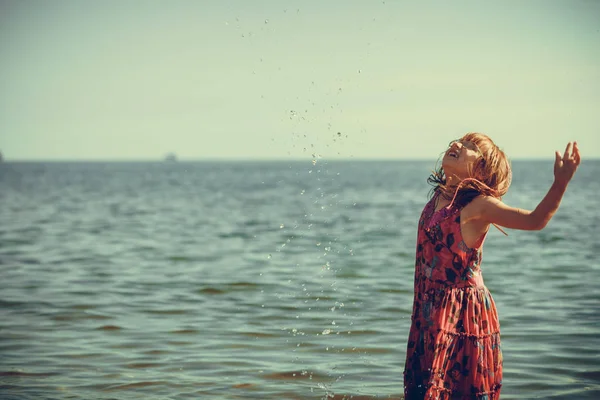 Kleuter meisje dragen jurkje spelen in water — Stockfoto