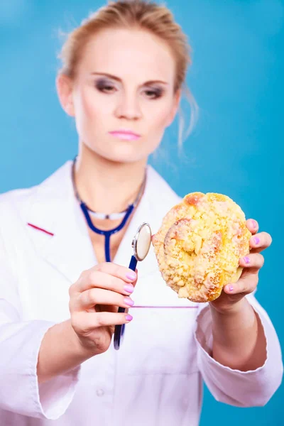 Dietista examinar pão doce com estetoscópio — Fotografia de Stock