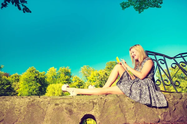 Kvinna sitter i parken, koppla av och använda telefon — Stockfoto