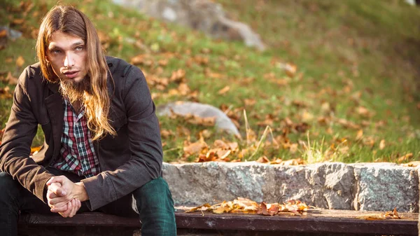 Sonbahar parkta bankta oturan adam uzun saçlı — Stok fotoğraf