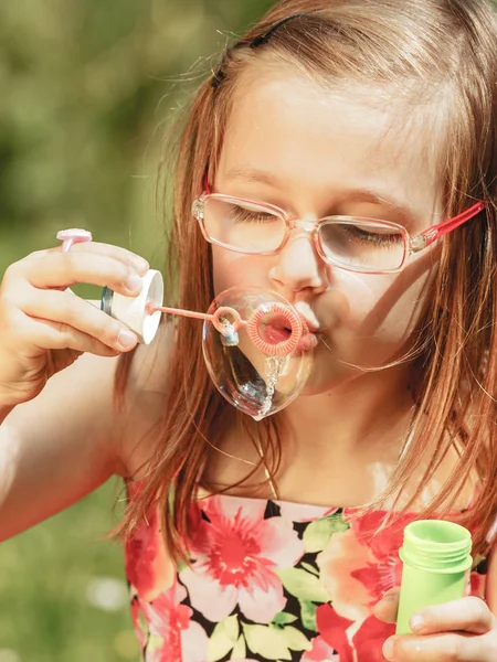 Little girl having fun blowing soap bubbles in park. — Stock Photo, Image