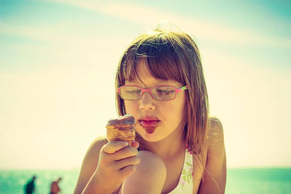 Ung flicka äta glass på stranden — Stockfoto