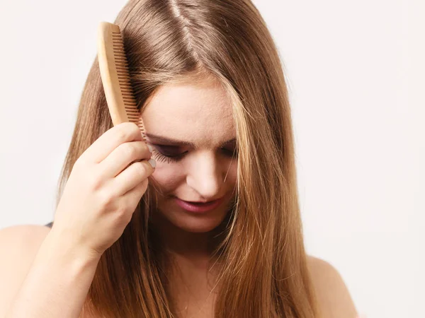 Mujer peinándose el pelo largo con peine de madera — Foto de Stock