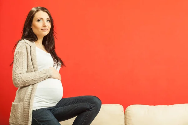 Sentado mulher grávida mostrando barriga — Fotografia de Stock