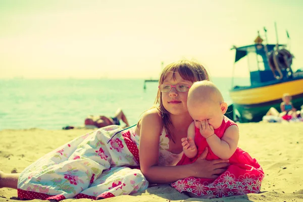 Småbarn flicka kramar lillasyster på stranden. — Stockfoto