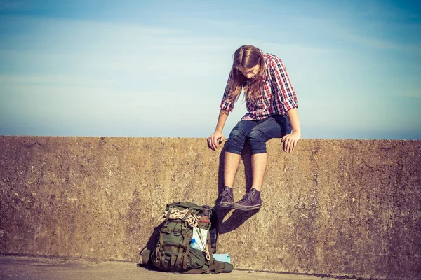 Man toeristische backpacker zittend op grunge muur buiten — Stockfoto