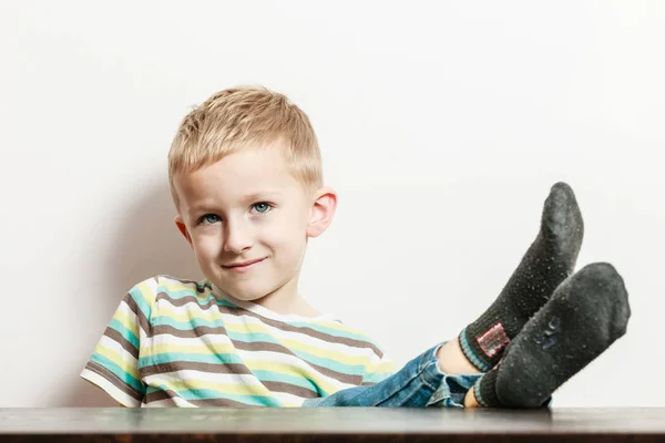 Kleiner Junge sitzt mit Beinen auf Tisch. — Stockfoto