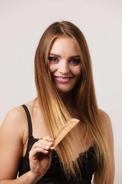 Mujer peinándose el pelo largo con peine de madera — Foto de Stock