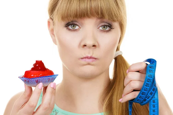 Frau hält Cupcake in der Hand und versucht der Versuchung zu widerstehen — Stockfoto