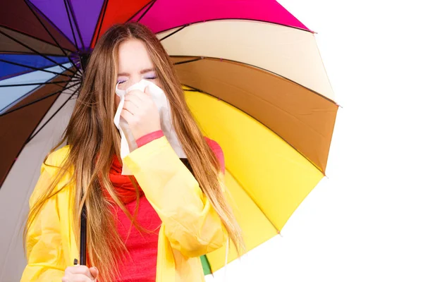Woman under umbrella sneezing in tissue — Stock Photo, Image