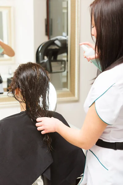 Hairdresser spraying conditioner on woman hair — Stock Photo, Image