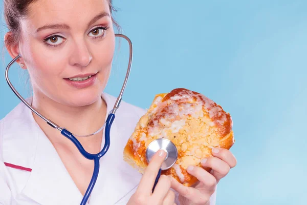 Ernährungsberaterin untersucht süße Brötchen mit Stethoskop. — Stockfoto