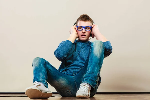 Joven con auriculares sentado en el suelo — Foto de Stock