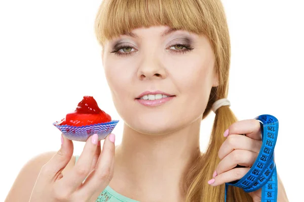 Woman holds cupcake and measuring tape. Diet — Stock Photo, Image