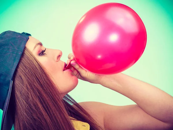 Female teenager inflating red balloon. — Stock Photo, Image