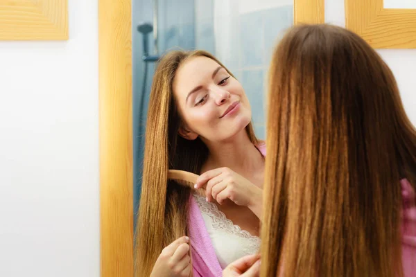 Frau kämmt ihre langen Haare im Badezimmer — Stockfoto