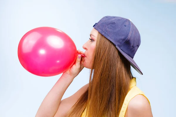 Mujer adolescente inflando globo rojo . — Foto de Stock