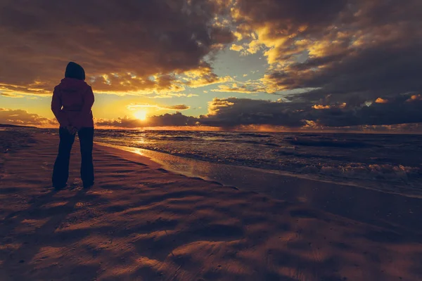 Frau genießt dramatischen Sonnenuntergang auf See — Stockfoto