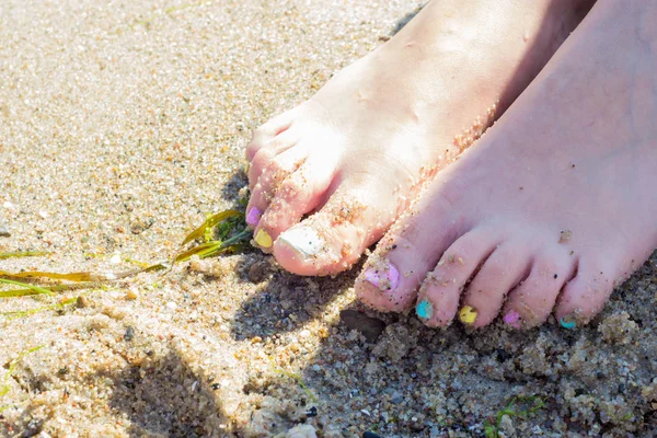 Frauenfüße mit Nagellack auf Sand — Stockfoto