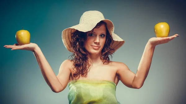 Женщина в платье и шляпе держать желтое яблоко — стоковое фото