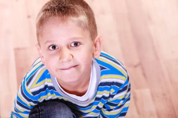 Jonge jongen zitten op houten vloer en glimlach. — Stockfoto