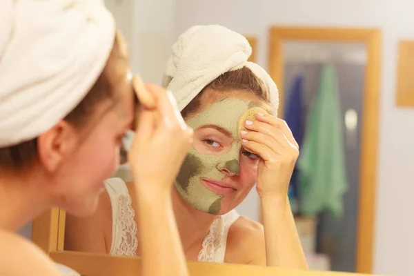 Mulher removendo máscara de barro facial lama no banheiro — Fotografia de Stock
