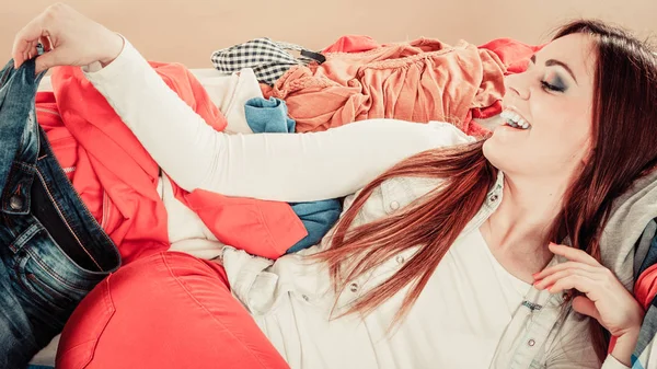 Kvinna ligga på soffan full av kläder. — Stockfoto